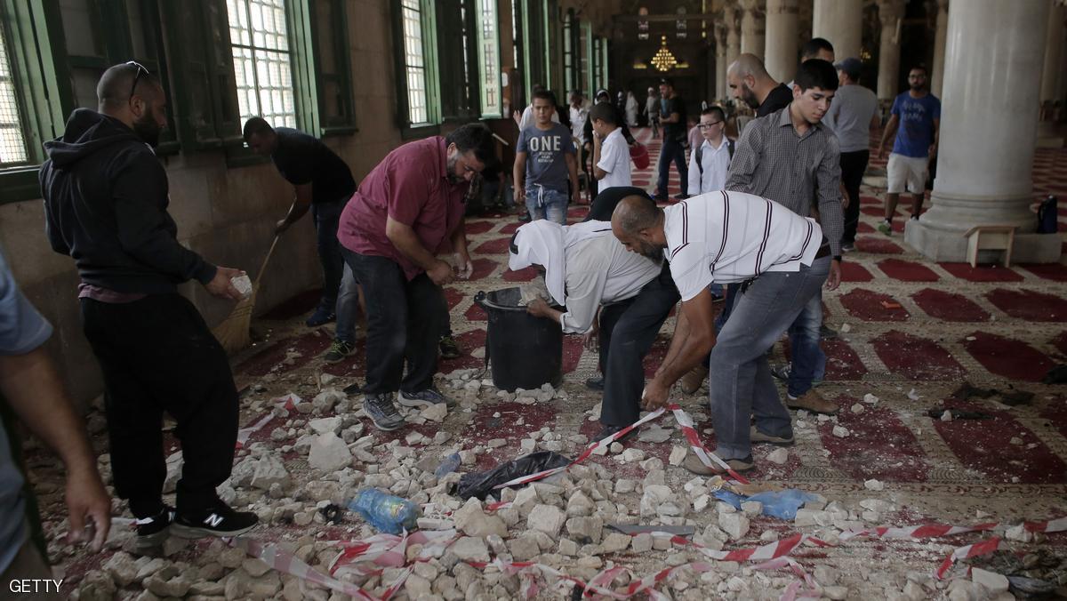 Palestinians clean up debris inside Al-Aqsa mosque in Jerusalem's Old City after clashes at the compound between Palestinians and Israeli police on September 13, 2015, just hours before the start of the Jewish New Year. The disturbances came with tensions running high after Israeli Defence Minister Moshe Yaalon last week outlawed the Murabitat (for females) and Murabitun groups which are made up of east Jerusalem Palestinians and Israeli Arabs and who confront Jewish visitors to the volatile Al-Aqsa mosque complex, considered Islam's third holiest shrine. AFP PHOTO / AHMAD GHARABLI (Photo credit should read AHMAD GHARABLI/AFP/Getty Images)