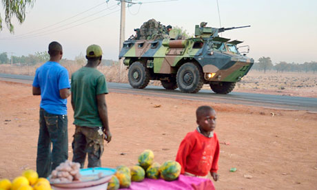 French soldiers on an armoured vehicle pass Malian people on their way to the north of Mali